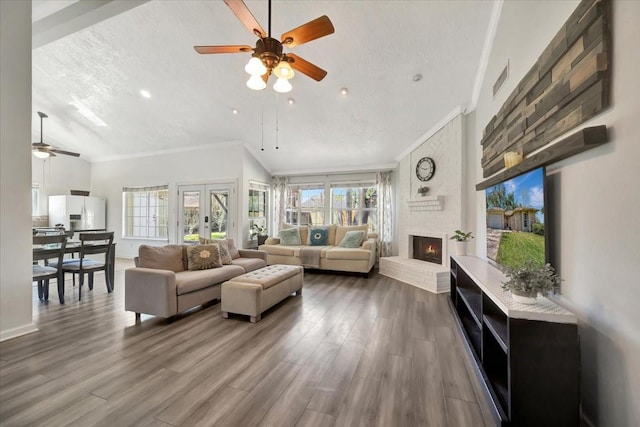 living room featuring a brick fireplace, a textured ceiling, crown molding, and wood finished floors