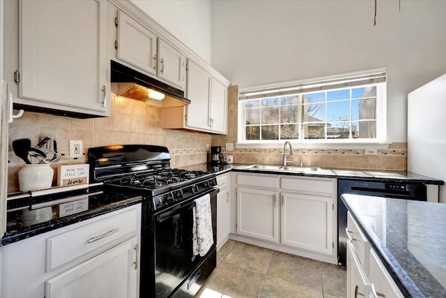 kitchen featuring black gas range, tasteful backsplash, under cabinet range hood, and a sink