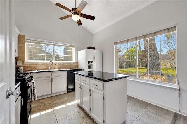 kitchen featuring black appliances, a sink, white cabinets, decorative backsplash, and vaulted ceiling