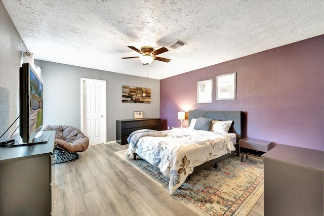 bedroom with visible vents, a textured ceiling, ceiling fan, and wood finished floors