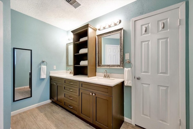 bathroom with a sink, visible vents, wood finished floors, and double vanity