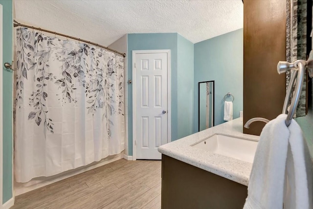 full bath featuring vanity, wood finished floors, and a textured ceiling