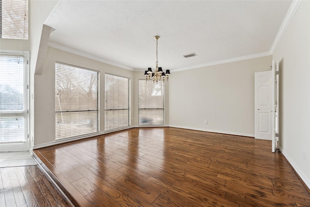 empty room featuring visible vents, crown molding, baseboards, a chandelier, and wood-type flooring