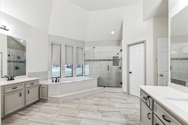 bathroom featuring a stall shower, high vaulted ceiling, a garden tub, and two vanities