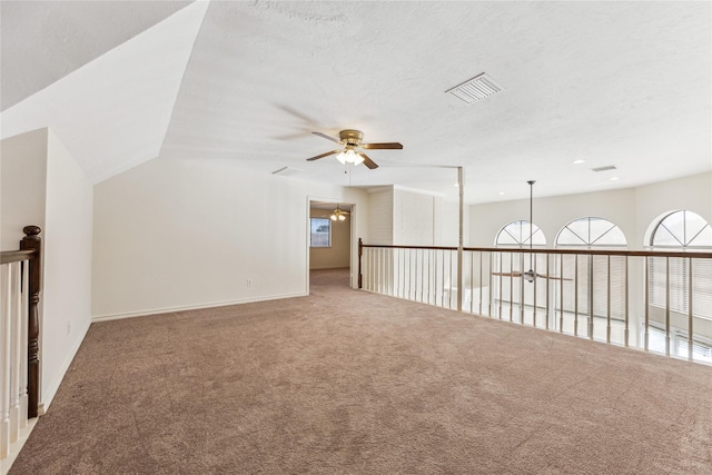 spare room featuring visible vents, a textured ceiling, carpet, lofted ceiling, and ceiling fan