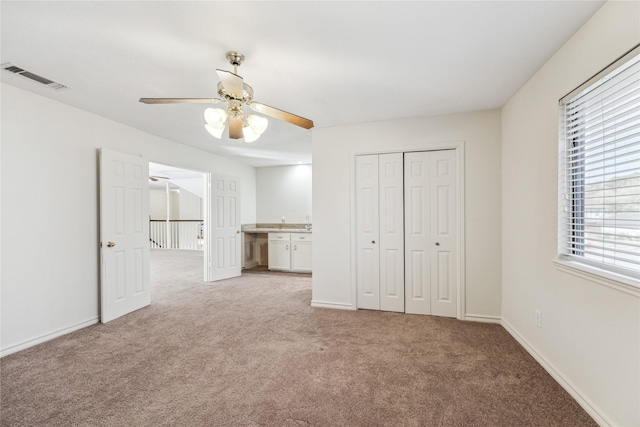 unfurnished bedroom featuring visible vents, light carpet, baseboards, and a closet