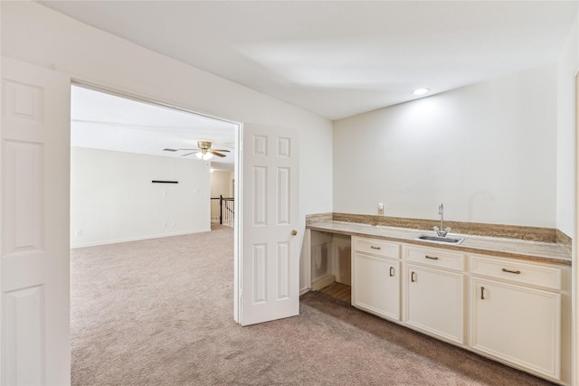 kitchen with ceiling fan, light countertops, light colored carpet, and a sink