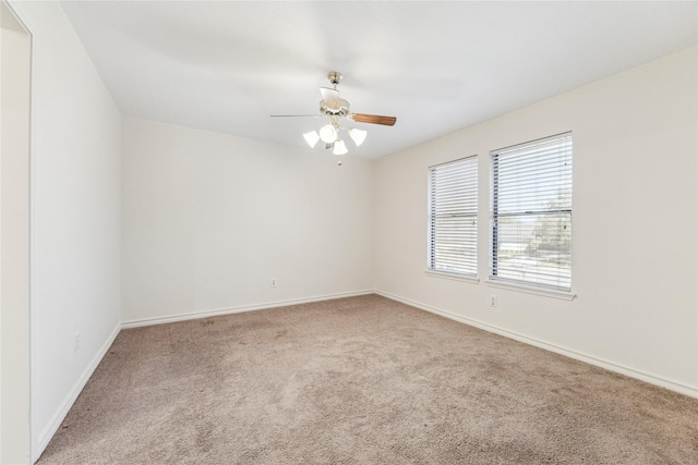 carpeted spare room featuring baseboards and ceiling fan