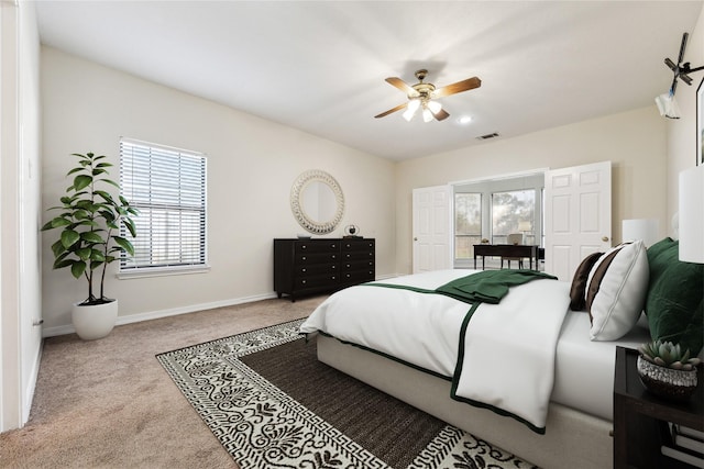 carpeted bedroom with visible vents, baseboards, and a ceiling fan