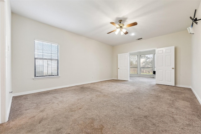 unfurnished room with baseboards, plenty of natural light, carpet floors, and a ceiling fan