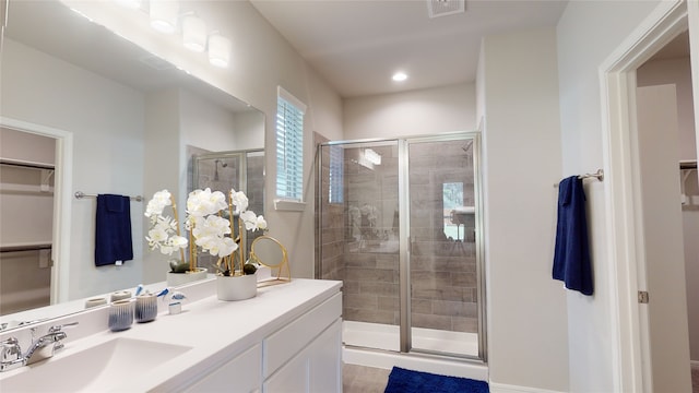 bathroom with visible vents, a spacious closet, a stall shower, and vanity