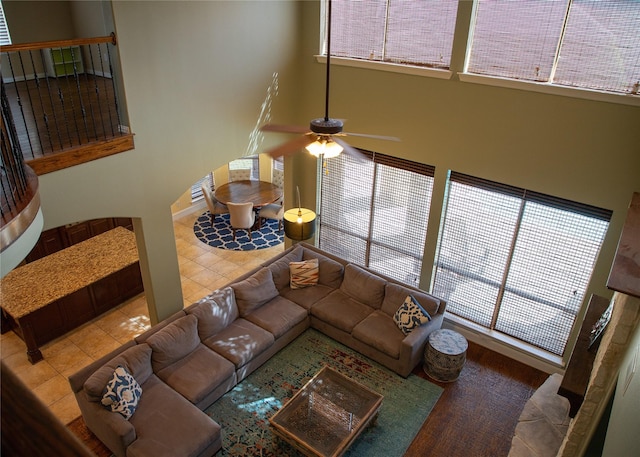 tiled living room featuring baseboards, a high ceiling, and a ceiling fan