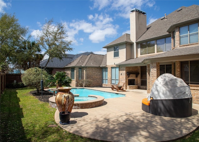 view of swimming pool with a yard, a pool with connected hot tub, a patio, and fence