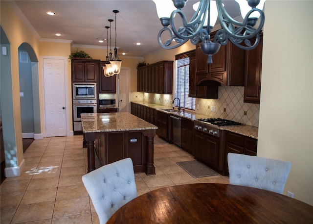 kitchen featuring a kitchen island, crown molding, appliances with stainless steel finishes, arched walkways, and a sink