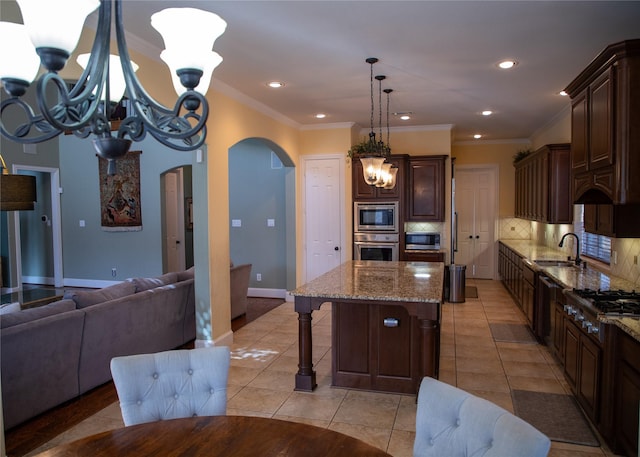 kitchen featuring backsplash, an inviting chandelier, arched walkways, stainless steel appliances, and a sink