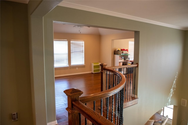 hall with an upstairs landing, wood finished floors, and crown molding