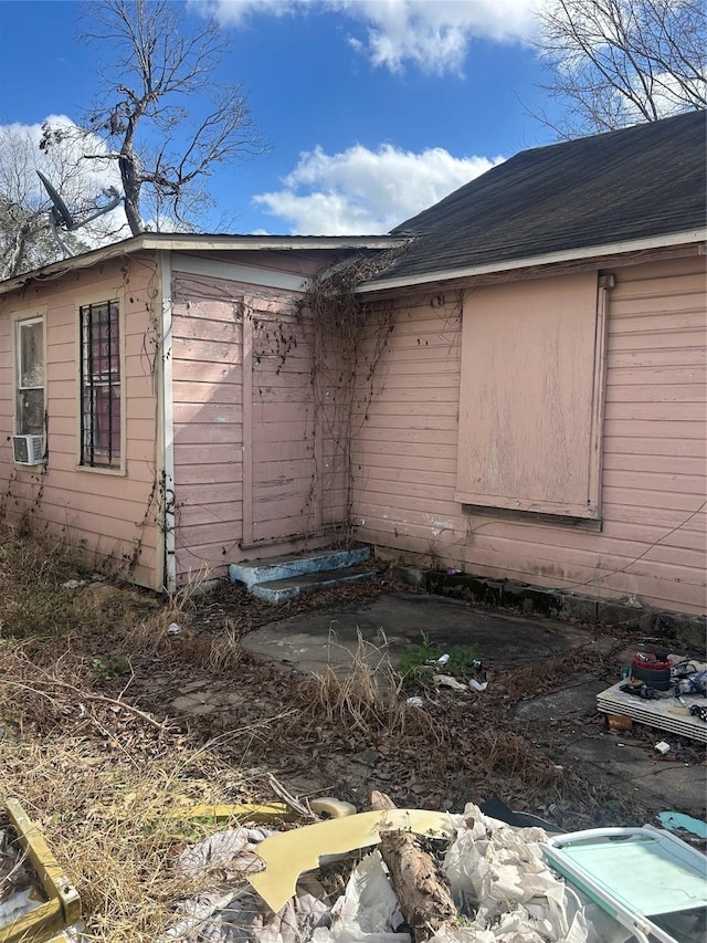 view of property exterior with cooling unit and roof with shingles