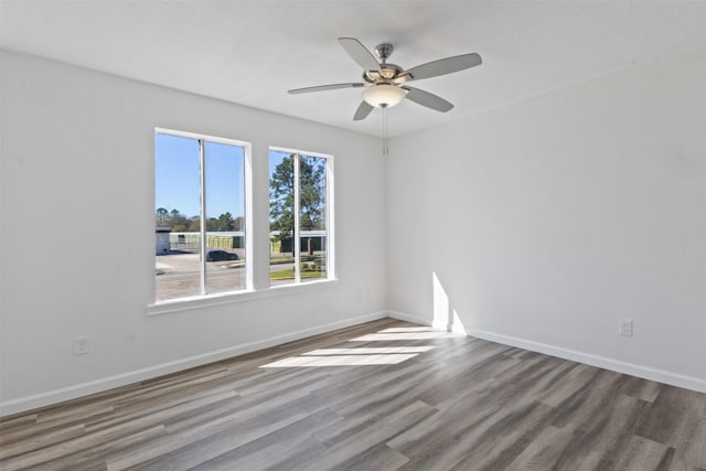 empty room featuring baseboards, wood finished floors, and a ceiling fan