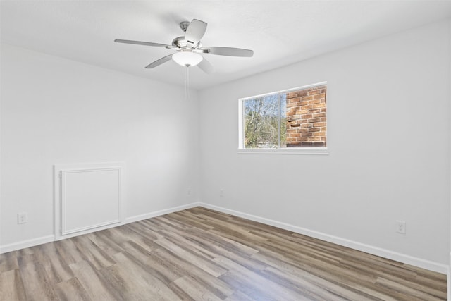 spare room featuring a ceiling fan, baseboards, and wood finished floors