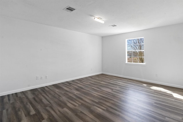 empty room featuring visible vents, a textured ceiling, baseboards, and dark wood-style flooring