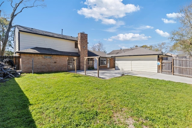 rear view of property with a gate, fence, a yard, brick siding, and a patio area