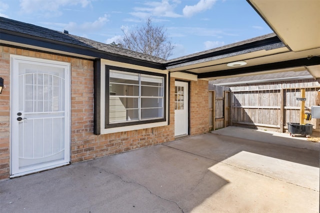 exterior space featuring a patio, a gate, brick siding, and roof with shingles