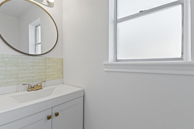 bathroom with decorative backsplash, a healthy amount of sunlight, and vanity