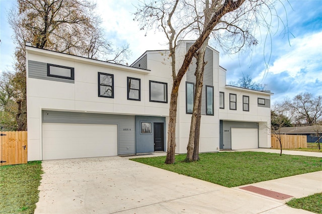 view of front of house featuring stucco siding, driveway, fence, a front yard, and an attached garage