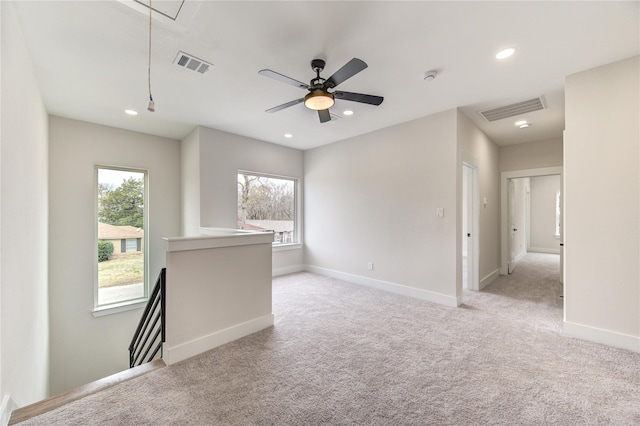 spare room featuring light carpet, visible vents, attic access, and baseboards