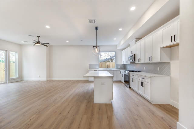 kitchen featuring tasteful backsplash, a kitchen island, light countertops, a wealth of natural light, and appliances with stainless steel finishes