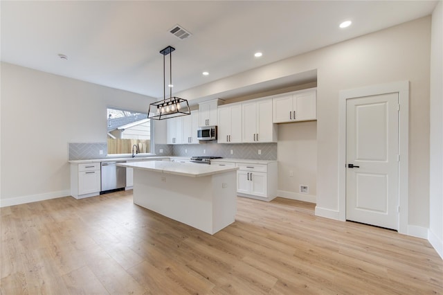 kitchen with tasteful backsplash, visible vents, light countertops, stainless steel appliances, and white cabinetry