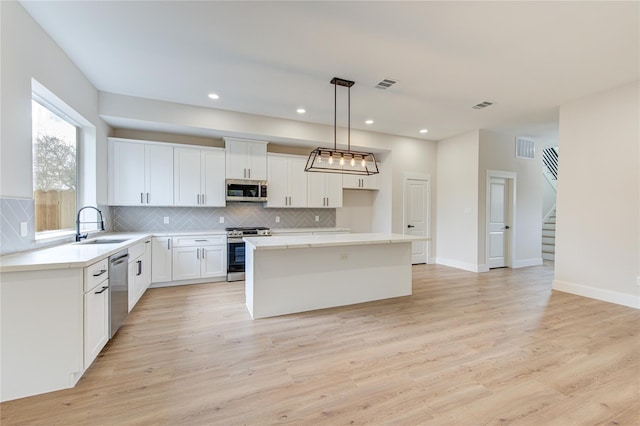 kitchen with visible vents, light wood-type flooring, stainless steel appliances, tasteful backsplash, and a center island