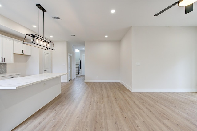 unfurnished living room featuring visible vents, baseboards, light wood-style floors, and a ceiling fan