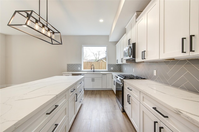 kitchen featuring a sink, stainless steel appliances, tasteful backsplash, and white cabinetry