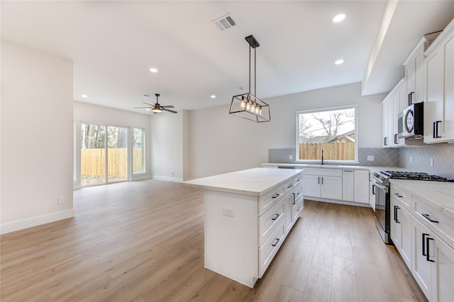 kitchen with visible vents, backsplash, light stone countertops, light wood-style flooring, and stainless steel appliances