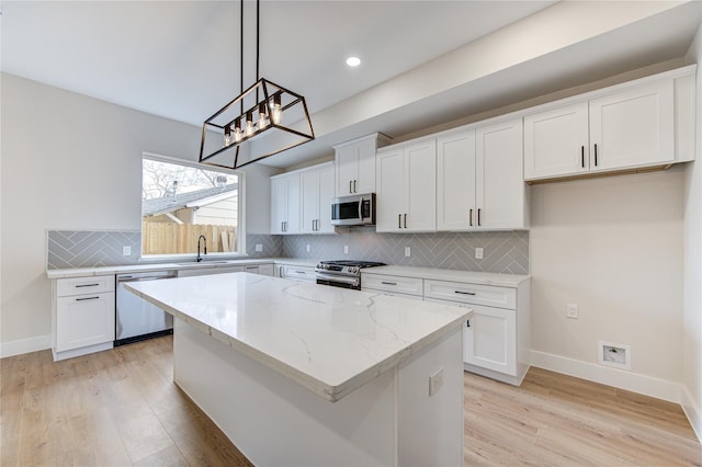 kitchen with light wood-style floors, stainless steel appliances, light stone countertops, and a kitchen island