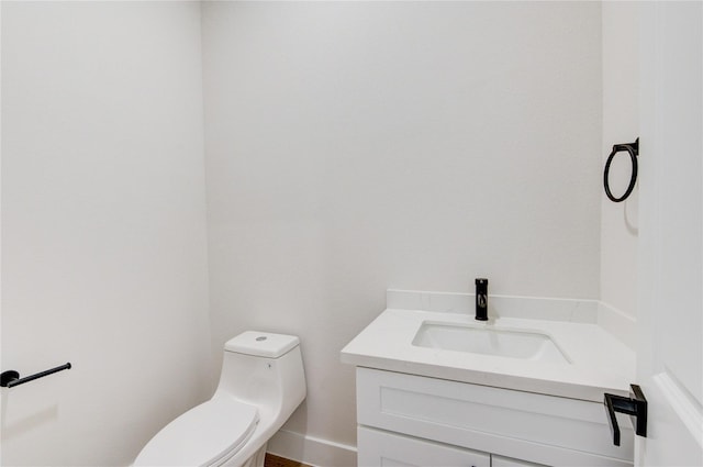 bathroom featuring toilet, vanity, and baseboards