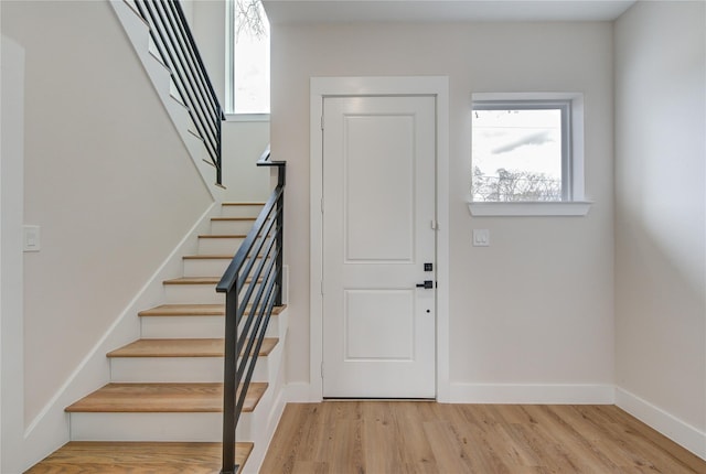 entrance foyer with stairway, light wood-style flooring, plenty of natural light, and baseboards