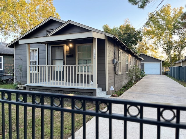 view of front of property with an outdoor structure, a detached garage, covered porch, and a fenced front yard