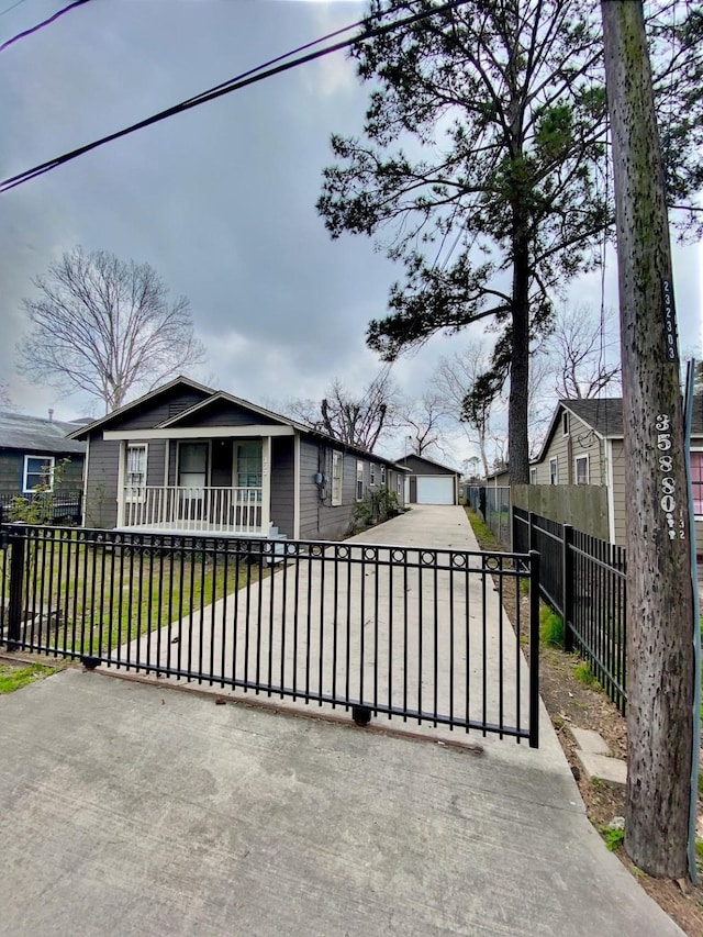 view of front of house featuring a front lawn, a fenced front yard, a garage, an outdoor structure, and driveway