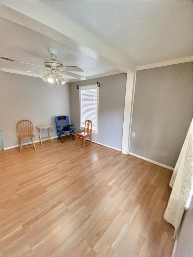 unfurnished room featuring a ceiling fan, visible vents, baseboards, light wood-style floors, and crown molding