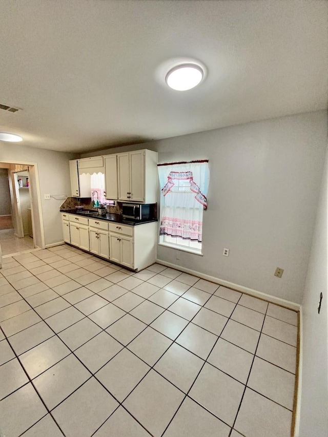 kitchen featuring visible vents, a sink, white cabinets, dark countertops, and stainless steel microwave