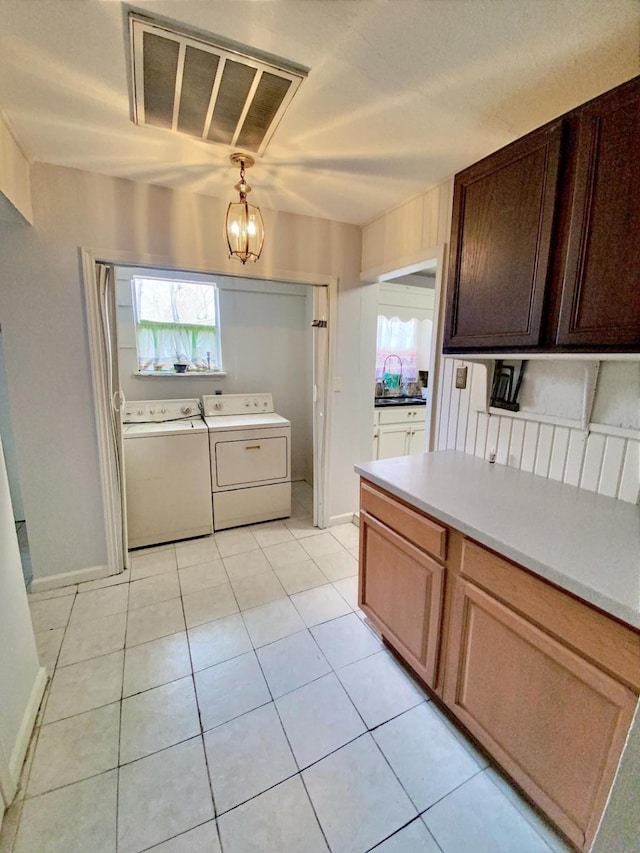 kitchen featuring washing machine and clothes dryer, visible vents, a healthy amount of sunlight, and light countertops