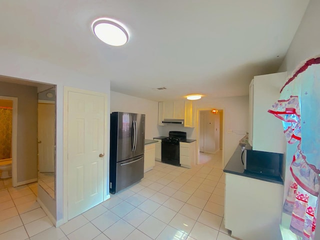 132 Grothe Ln, Houston, TX 77022 - kitchen featuring freestanding refrigerator, gas stove, light tile patterned flooring, under cabinet range hood, and white cabinets