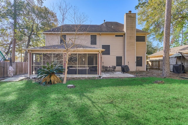 back of property with a fenced backyard, a chimney, a yard, and a sunroom