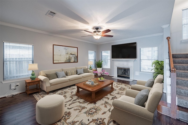 living area featuring a ceiling fan, wood finished floors, visible vents, ornamental molding, and stairs