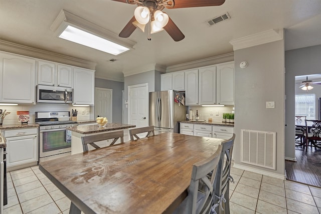 kitchen with a kitchen island, visible vents, stainless steel appliances, and light tile patterned floors