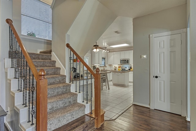 stairs with visible vents, baseboards, a ceiling fan, and wood finished floors