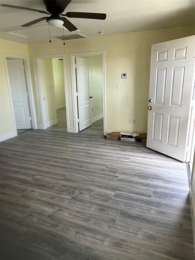 unfurnished bedroom with visible vents, baseboards, wood finished floors, and a ceiling fan