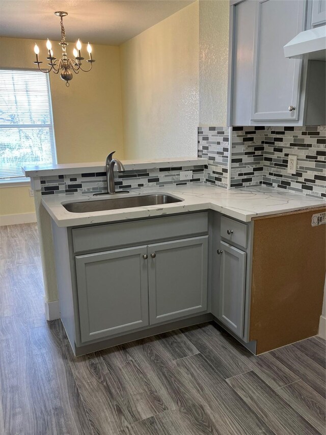 kitchen featuring a sink, backsplash, gray cabinetry, and extractor fan